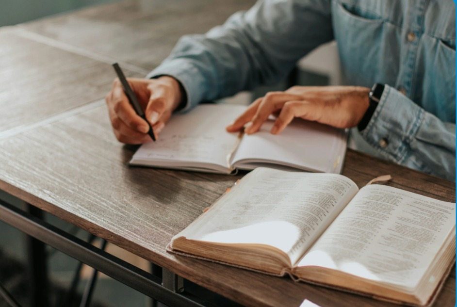 Student studying with notebook and open book on a desk
